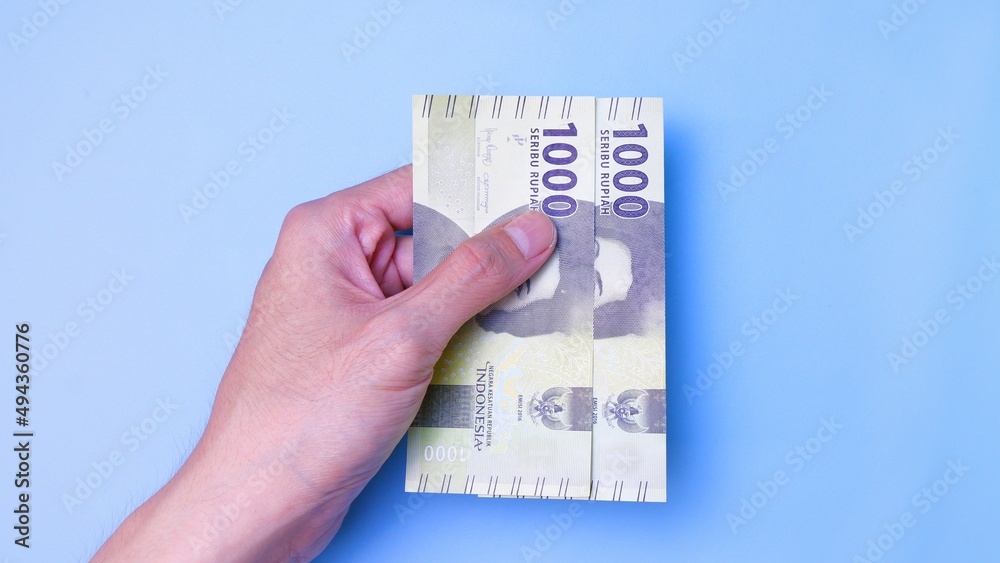 Indonesian Rupiah the official currency of Indonesia. Man's hand is making a payment. Business Loan Income Money Investment Economy and Finance Concept Uang 1000 1.000 Rupiah. Prosperity Concept. Indonesian Rupiah the official currency of Indonesia. Man's hand is making a payment. Business Loan Income Money Investment Economy and Finance Concept Uang 1000 1.000 Rupiah. Prosperity Concept.