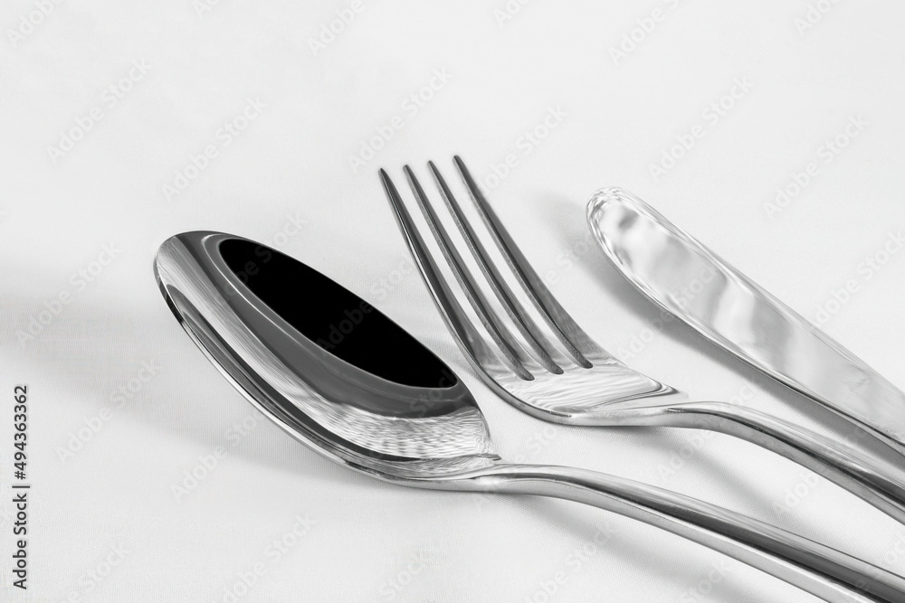 Closeup of a set of shiny silverware on white background with copy space. Closeup of a set of shiny silverware on white background with copy space.