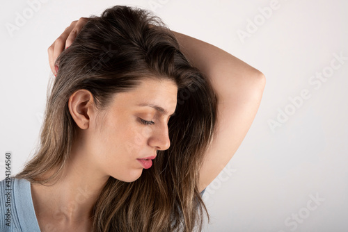 Young woman touching her blond hair, serious and sensual expression, on pure background