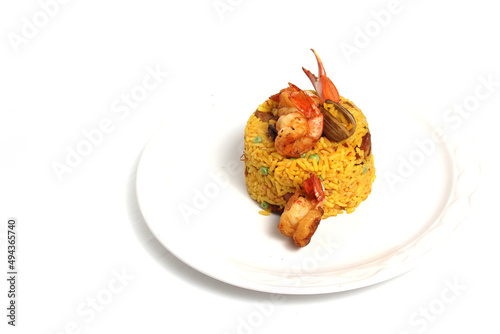 Paella rice is a traditional cuisine recipe from the city of Valencia Spain prepared with saffron, seafood, shrimp, vegetables served on a white plate
