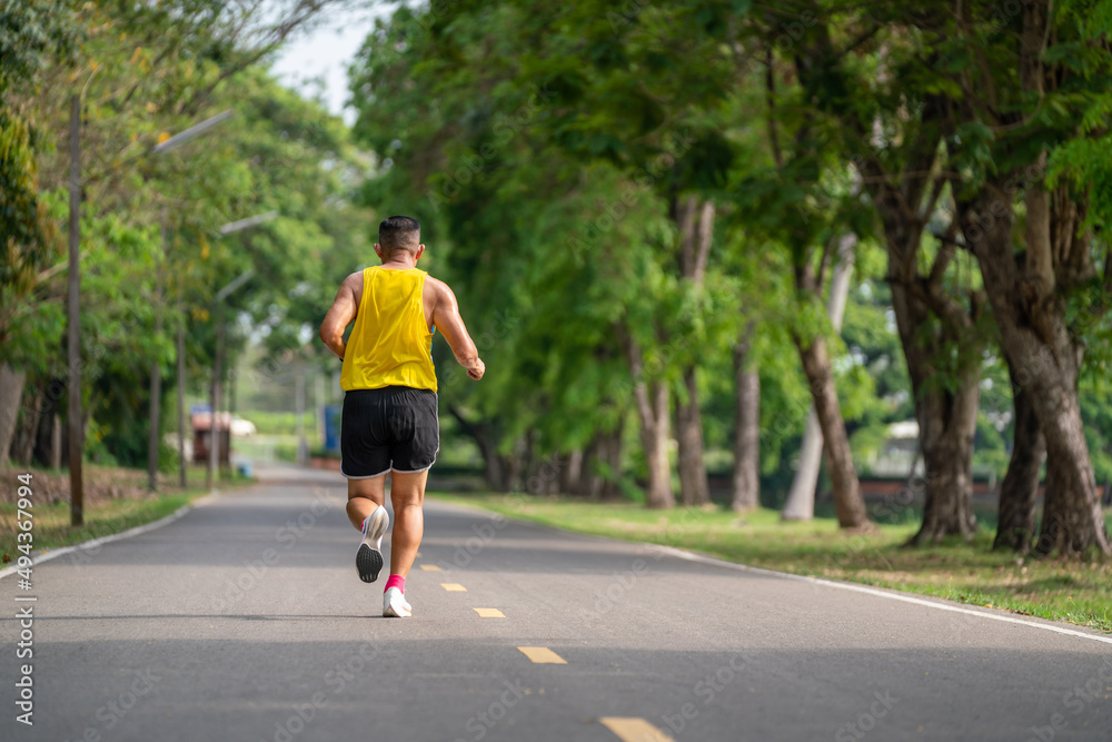 Backside of senior man in fitness wear running in a park. Healthy lifestyle concept.