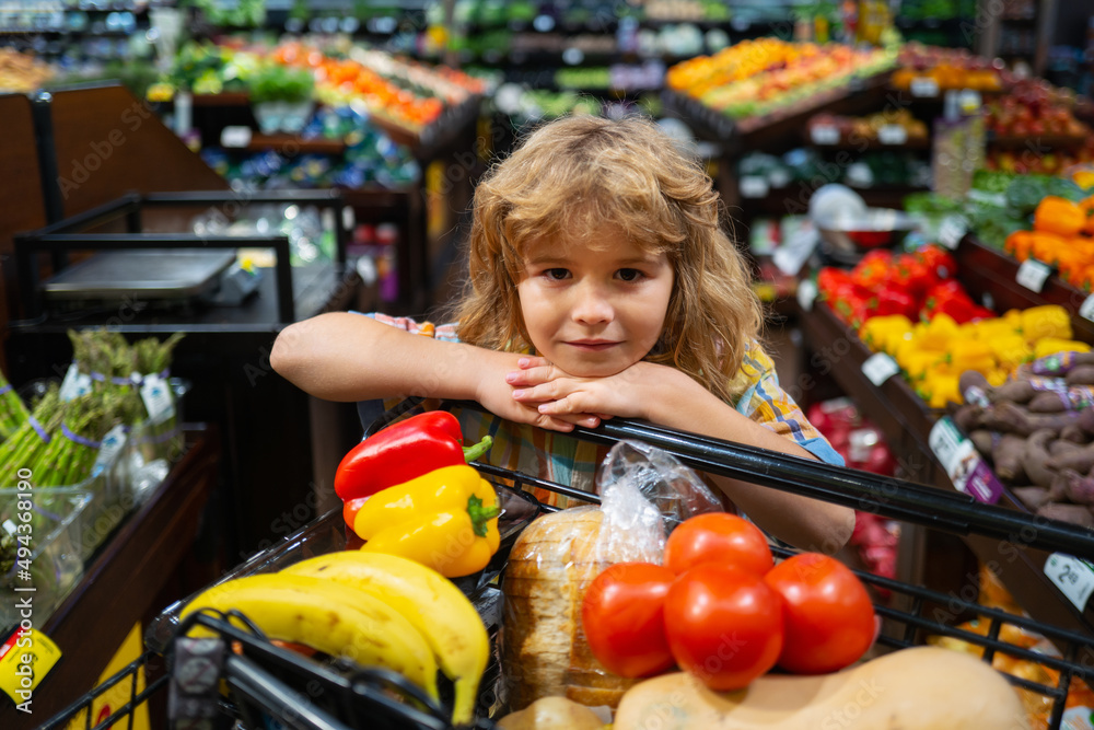 Child buying fruit in supermarket. Kid buy fresh vegetable in grocery store. Kids in shop, healthy food. Shopping cart, grocery store concept. Child buying fruit in supermarket. Kid buy fresh vegetable in grocery store. Kids in shop, healthy food. Shopping cart, grocery store concept.