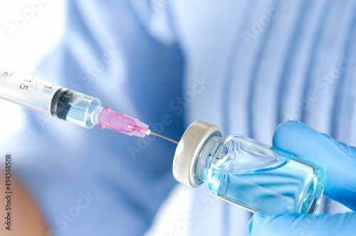 doctor's hand holds a syringe and a blue vaccine bottle at the hospital. Health and medical concepts.