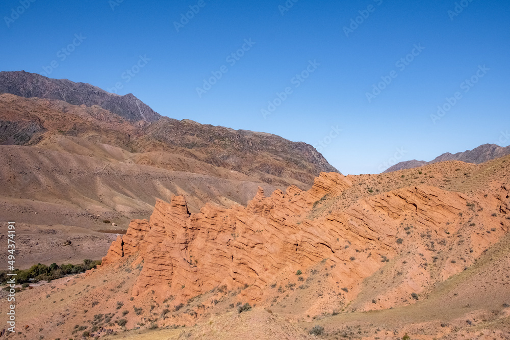 Beautiful red clay mountains eroded on wind. Red mountains or red canyon on the way from Assy plateau to Bartogai reservoir. Mountain canyon landscape. Beautiful red clay mountains eroded on wind. Red mountains or red canyon on the way from Assy plateau to Bartogai reservoir. Mountain canyon landscape.