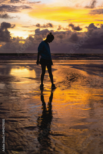 Beautiful young woman at sunset on the ocean, Bali, Indonesia.