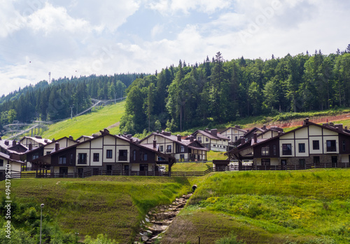 Scenic summer view of winter mountain ski resort with house cottages with forest and skiing slope in Bukovel, Ukraine. 