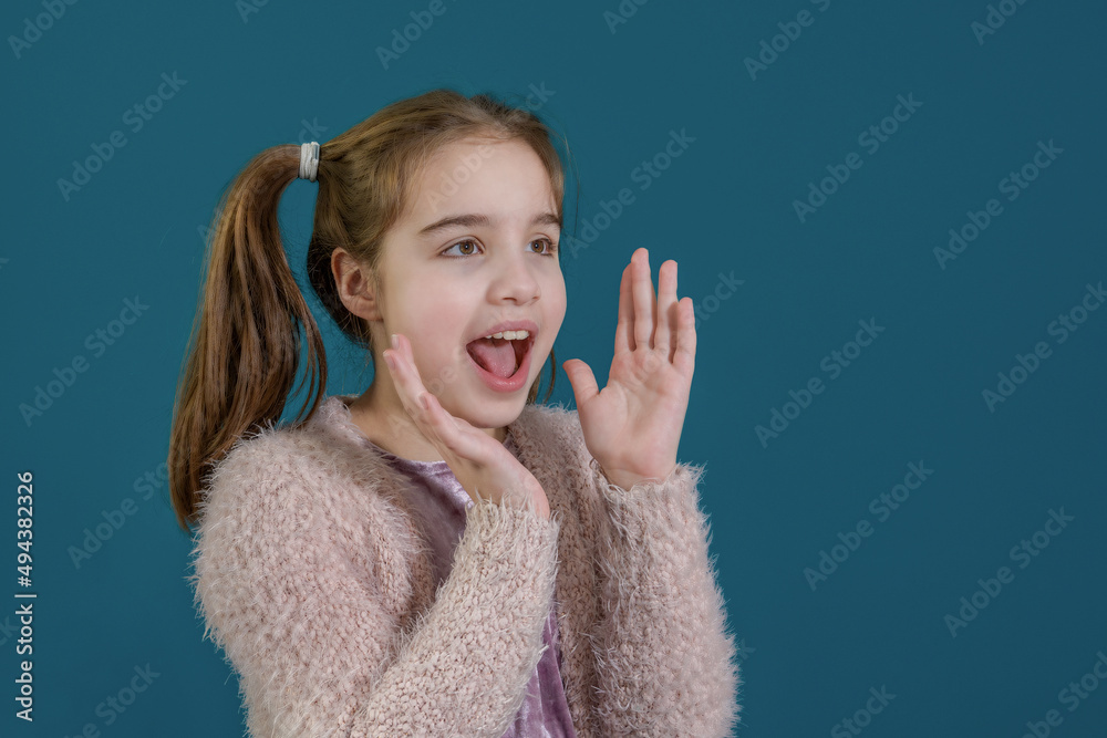 Portrait of lovely, cute, teenage girl in pink sweater with open mouth and big eyes isolated on blue background Portrait of lovely, cute, teenage girl in pink sweater with open mouth and big eyes isolated on blue background