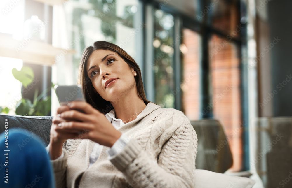Maybe its time I sent that message. Shot of an attractive young woman looking thoughtful and sending text messages while relaxing on her sofa at home. Maybe its time I sent that message. Shot of an attractive young woman looking thoughtful and sending text messages while relaxing on her sofa at home.