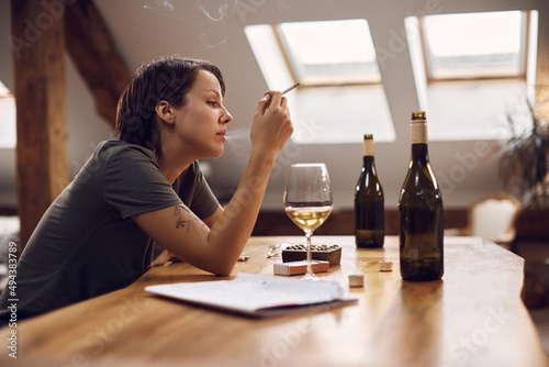 Obraz na plátně Young desperate woman smoking cigarette and drinking alcohol at home
