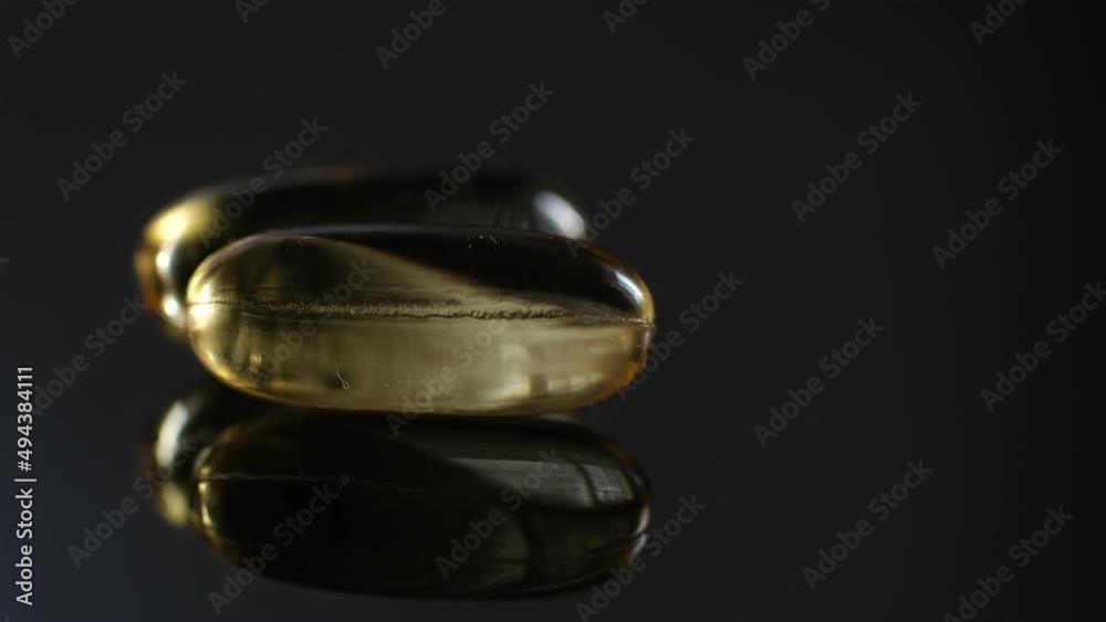 Omega 3 Gold oil capsules on black background, rotation. Close-up of rotating golden pills.Vitamins supplements pills omega 3. Cod liver oil medicines. Fish oil capsules.Omega 3 Fish oil vitamin gel Omega 3 Gold oil capsules on black background, rotation. Close-up of rotating golden pills.Vitamins supplements pills omega 3. Cod liver oil medicines. Fish oil capsules.Omega 3 Fish oil vitamin gel