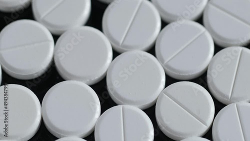 Many white round pills. Pharmaceutical production. Drugs on the production line. Moving background. close-up. view from above. white medical pills rotating closeup. Pills and drugs. Pharmaceutical photo