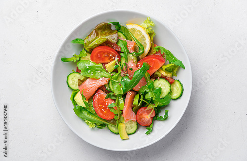 Salad with salmon, avocado, tomatoes, fresh herbs and sesame flax seeds.