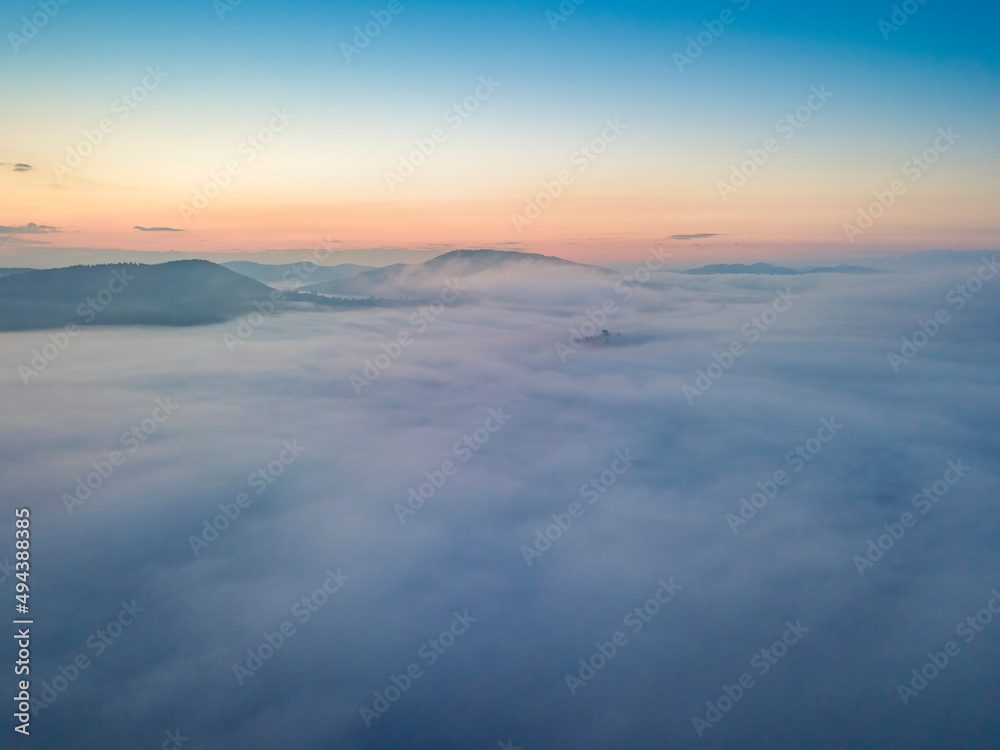 The rays of dawn over the fog in the Ukrainian Carpathians. Aerial drone view.