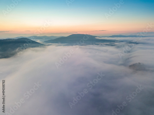 The rays of dawn over the fog in the Ukrainian Carpathians. Aerial drone view. © Sergey