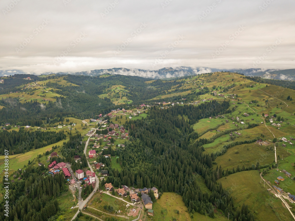Obraz premium Green slopes of Ukrainian Carpathian mountains in summer. Cloudy morning, low clouds. Aerial drone view.