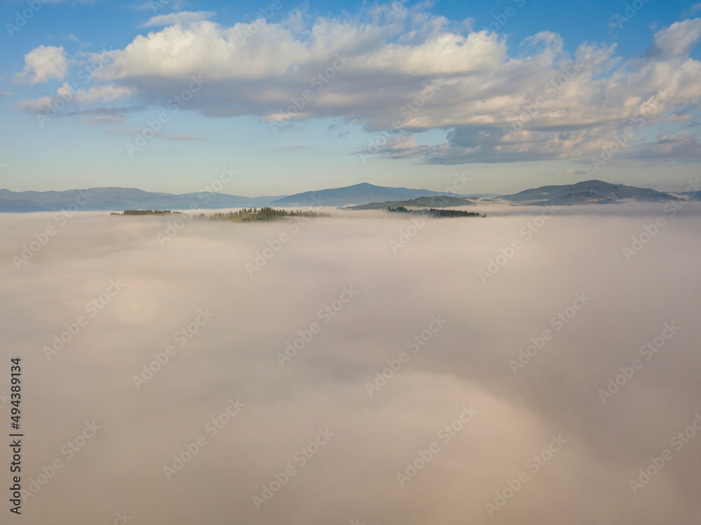 Flight over fog in Ukrainian Carpathians in summer. Mountains on the horizon. A thick layer of fog covers the mountains with a continuous carpet. Aerial drone view. Flight over fog in Ukrainian Carpathians in summer. Mountains on the horizon. A thick layer of fog covers the mountains with a continuous carpet. Aerial drone view.