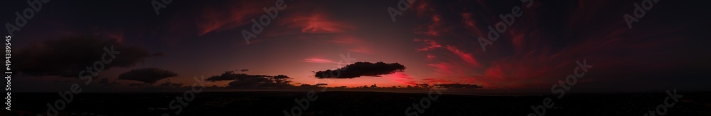Deep reds and purples panoramic view of silhouetted clouds at the sunset afterglow