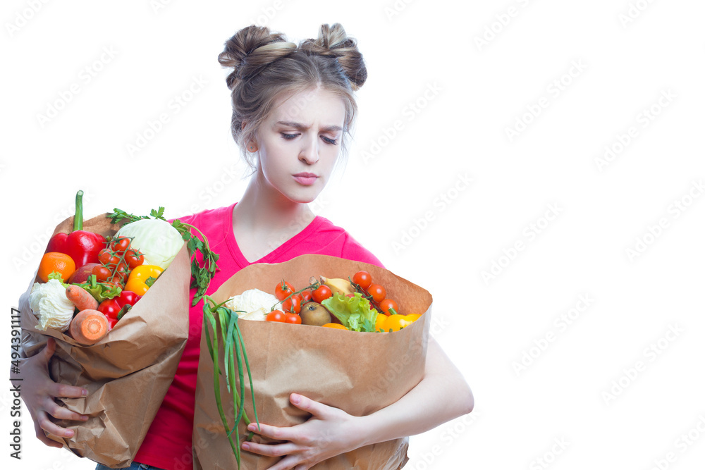 Vegan Healthy Lifestyle. Embarrassed Caucasian Blond Girl Holding Two Eco Paper Bags with Vegetables and Groceries And Thinking On White Background Vegan Healthy Lifestyle. Embarrassed Caucasian Blond Girl Holding Two Eco Paper Bags with Vegetables and Groceries And Thinking On White Background