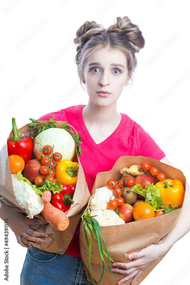 Healthy Lifestyle. Embarrassed Caucasian Blond Girl Holding Two Eco Paper Bags with Vegetables and Groceries And Thinking On White Background. Healthy Lifestyle. Embarrassed Caucasian Blond Girl Holding Two Eco Paper Bags with Vegetables and Groceries And Thinking On White Background.