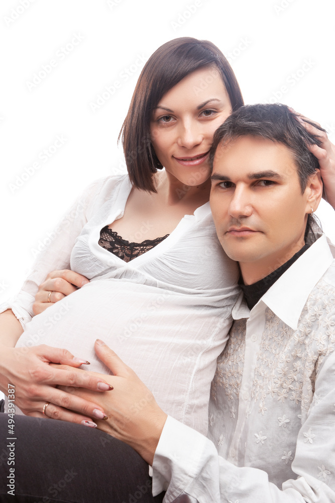 Closeup of Loving Caucasian Couple with Pregnant Wife Woman Interacting While Sitting While Touching Belly Embraced Against White Background. Closeup of Loving Caucasian Couple with Pregnant Wife Woman Interacting While Sitting While Touching Belly Embraced Against White Background.