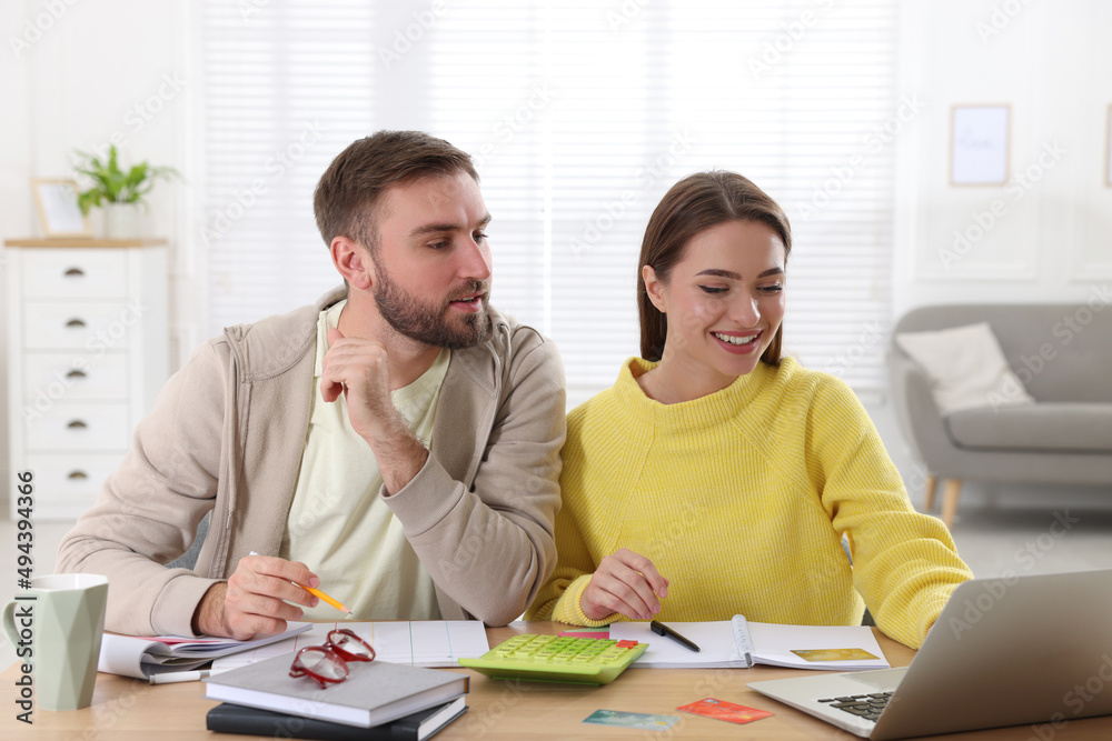 Young couple discussing family budget at table in living room Young couple discussing family budget at table in living room