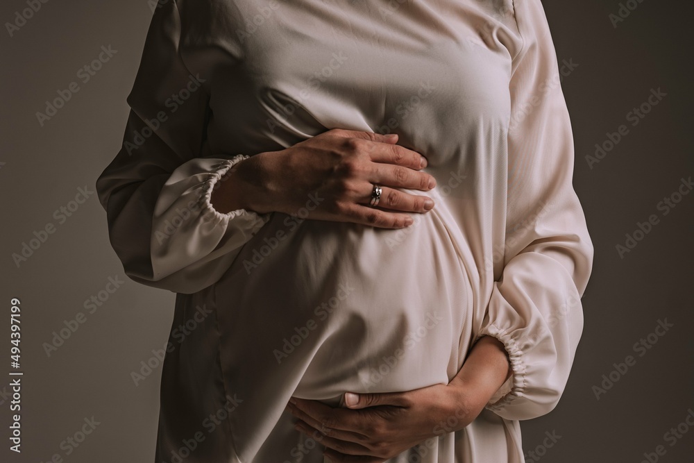 a pregnant woman holds her hands on her stomach