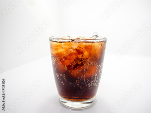 Close-up and isolated in the middle, soft drink and ice in clear curved glass, white background