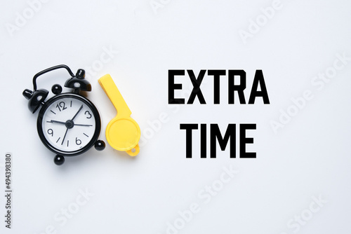 A picture of alarm clock and whistle with the word extra time. Extra time concept.