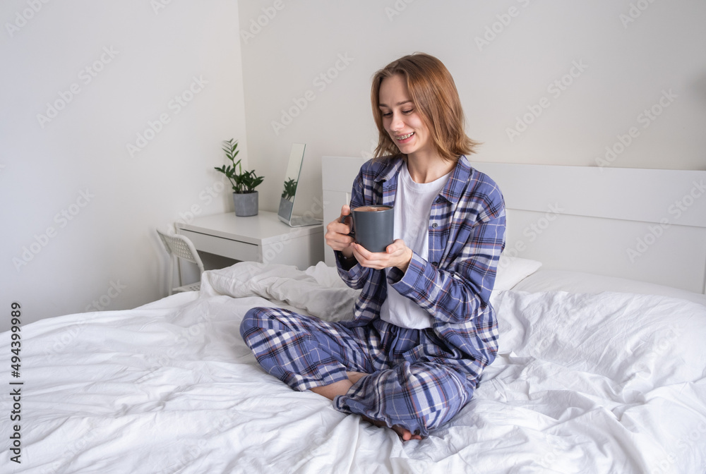 A beautiful girl drinking coffee in her bed in the morning. A young woman wakes up in her bedroom with a cup of an invigorating beverage. A beautiful girl drinking coffee in her bed in the morning. A young woman wakes up in her bedroom with a cup of an invigorating beverage.