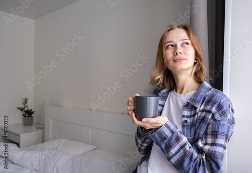A beautiful girl drinking coffee in her bed in the morning. A young woman wakes up in her bedroom with a cup of an invigorating beverage.