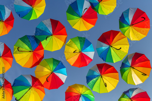 Rainbow-colored umbrellas in the blue sky