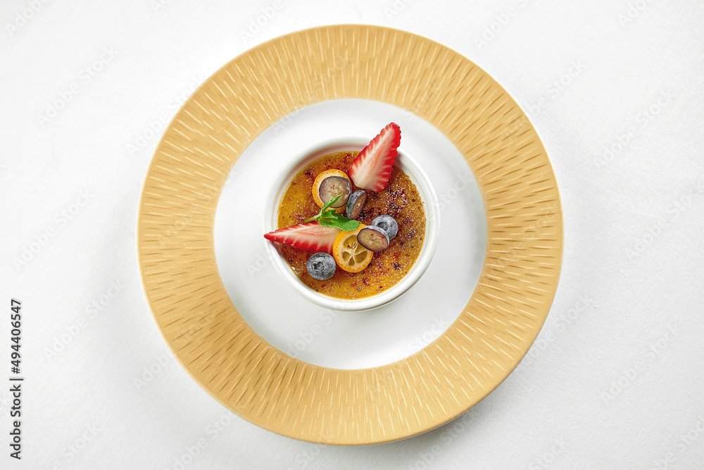 Dessert creme brulee in a plate on a white tablecloth. Close-up Dessert creme brulee in a plate on a white tablecloth. Close-up