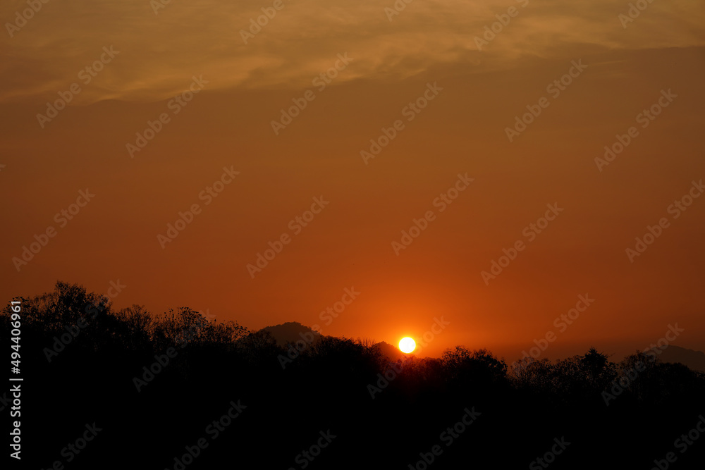 Sunset view with silhouettes of mountains, beautiful golden rays of sun in the background.
