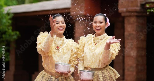 Handheld shot, front view, Young beautiful women with Thai Traditional costume enjoy to splashing water in the temple on Songkran festival. Thai New Year, Thailand culture with Water festival