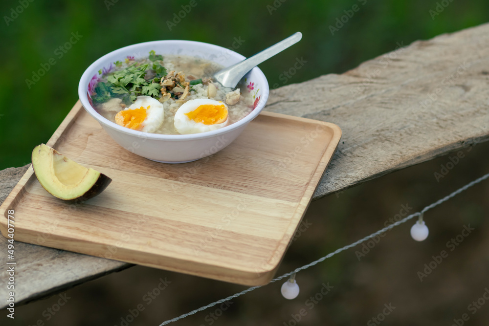 Porridge in a serving bowl with avocado on a wooden tray looks beautiful. Breakfast at a hill tribe house in Thailand Porridge in a serving bowl with avocado on a wooden tray looks beautiful. Breakfast at a hill tribe house in Thailand