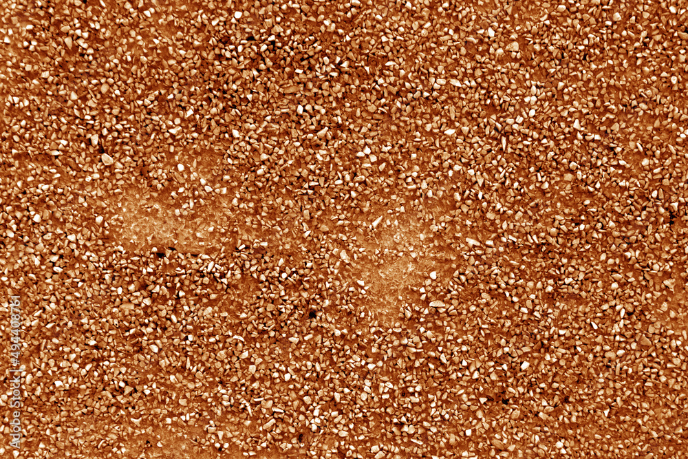 Wall made of small crushed stones and concrete in orangee tone.