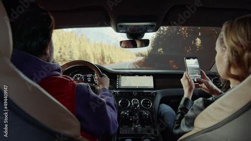 A passenger photographs a forest road from a Bentley car
