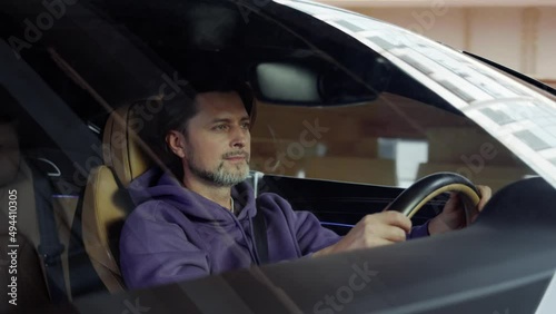 The driver of the Bentley, looks around while driving. Background,city,buildings