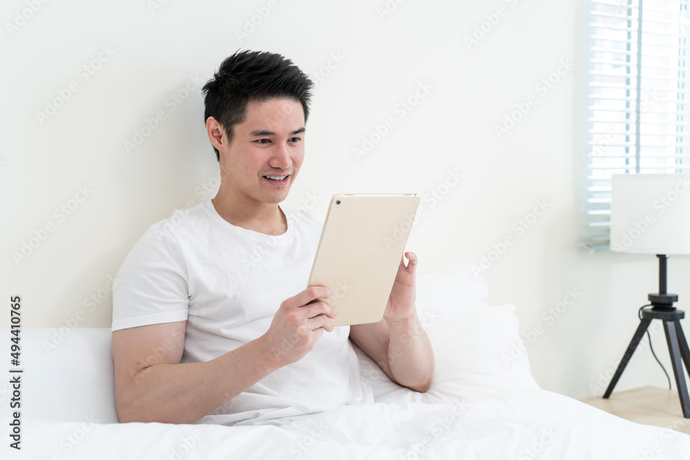 Asian handsome man read online news from tablet in morning at home. Asian handsome man read online news from tablet in morning at home.