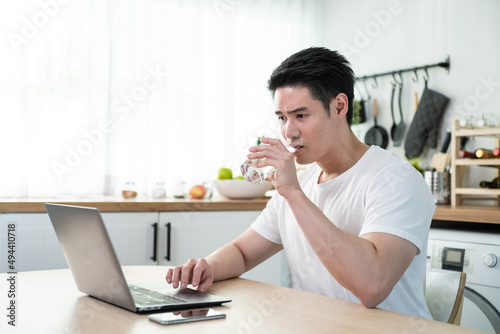 Asian business man drinking miniral water while sit working from home.  photo