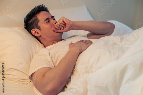 Asian sick handsome male in pajamas sleep in the dark night in bedroom