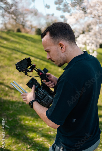 professional tv camera man filming with a cinema camera during summer outdoors