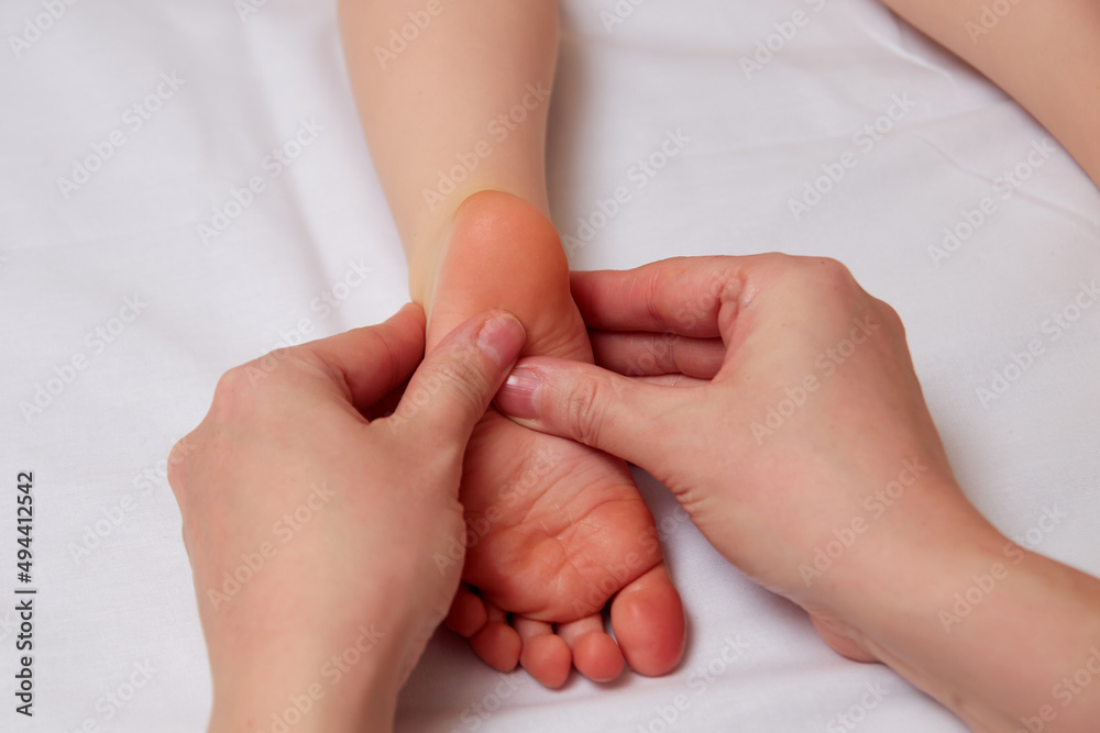 Doctor performing pediatric foot massage to prevent development of flat feet Doctor performing pediatric foot massage to prevent development of flat feet