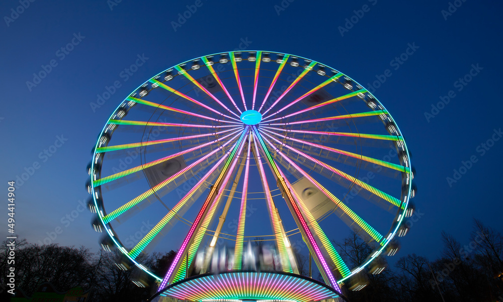 Fototapeta premium huge colorful ferriswheel rotating on a funfair in a blue summer night