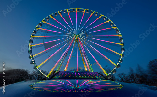 huge colorful ferriswheel rotating on a funfair in a blue summer night