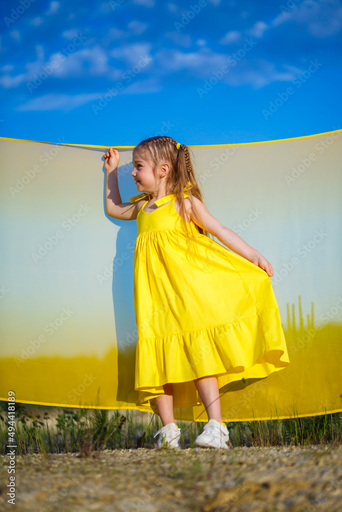 Ukrainian girl 7 years old, she is a patriot of Ukraine, dressed in a yellow dress against a blue sky. Blue sky. Sunny day. Free Ukrainian child. Child symbol of Ukraine Ukrainian girl 7 years old, she is a patriot of Ukraine, dressed in a yellow dress against a blue sky. Blue sky. Sunny day. Free Ukrainian child. Child symbol of Ukraine