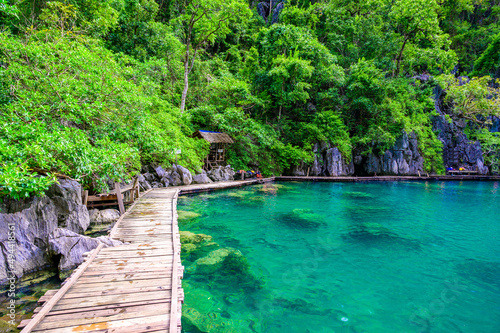 Kayangan Lake - Blue crystal water in paradise lagoon - walkway on wooden pier in tropical scenery - Coron island, Palawan, Philippines. photo