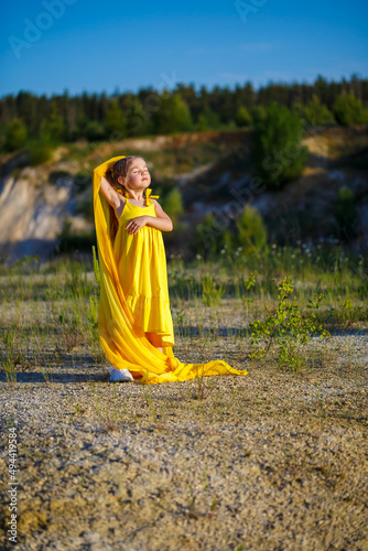 The symbol of freedom is a Ukrainian girl of 7 years old, patriotically dressed in a yellow dress against a blue sky. Blue sky. Sunny day. Free Ukrainian child. Child symbol of Ukraine