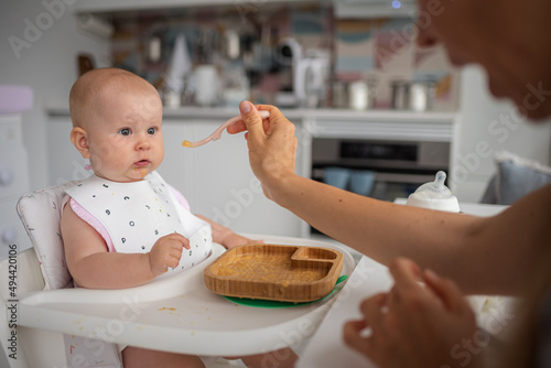 baby's first feeding, mom feeds a surprised baby with a spoon