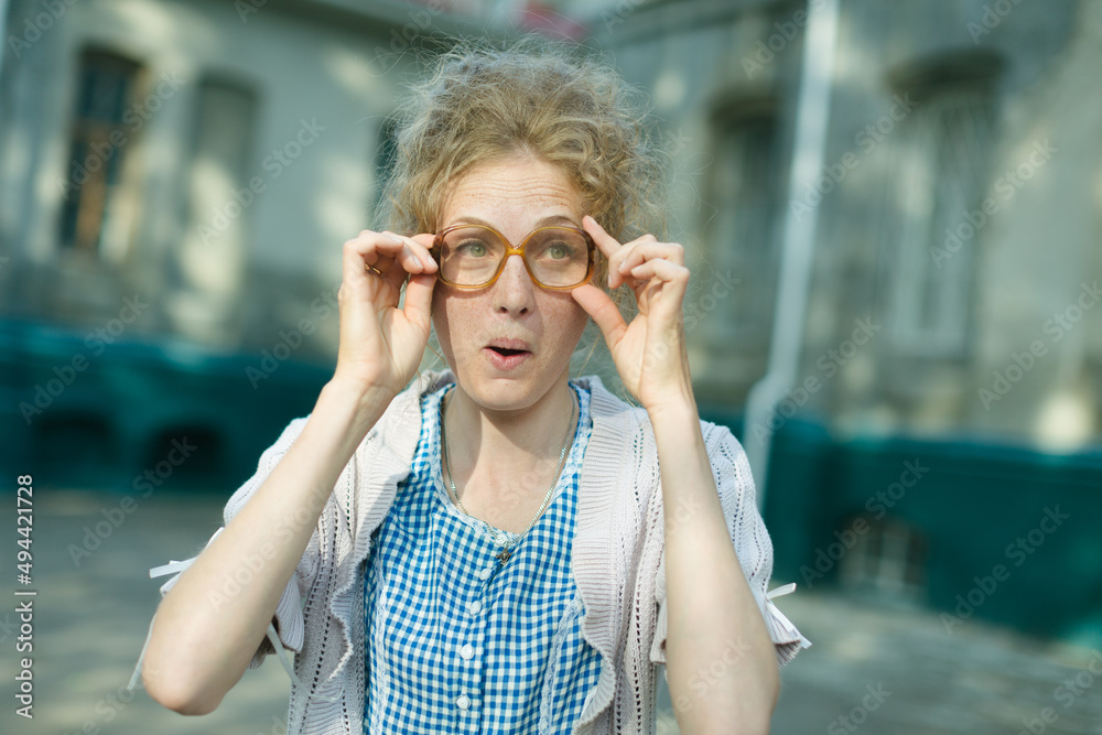 cheerful girl with poor eyesight on the street does not see well, expressing emotions. glasses concept cheerful girl with poor eyesight on the street does not see well, expressing emotions. glasses concept